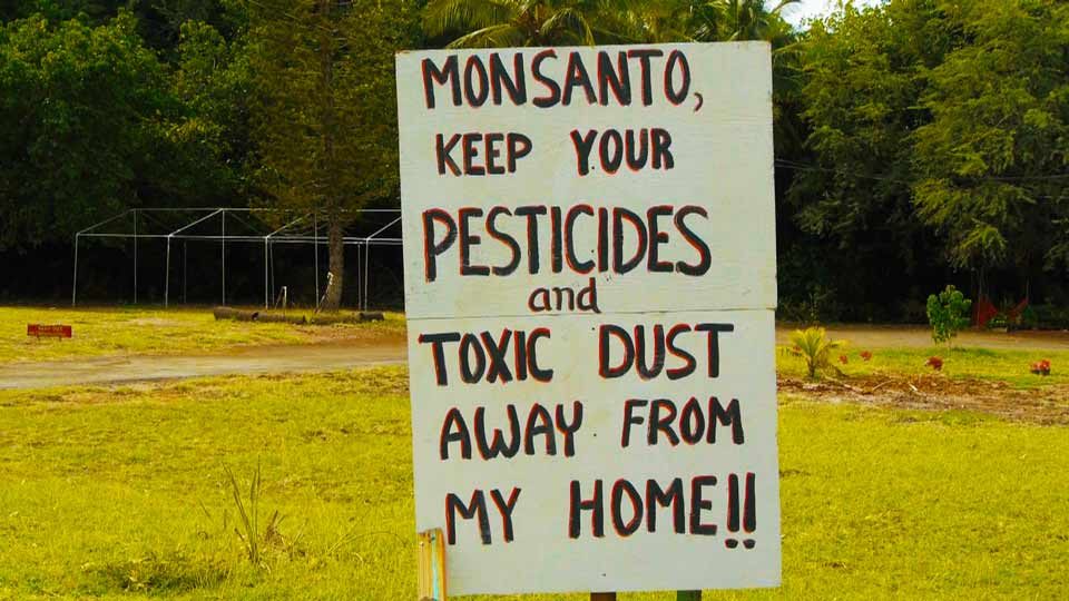 Hand-painted roadside sign protesting pesticide drift